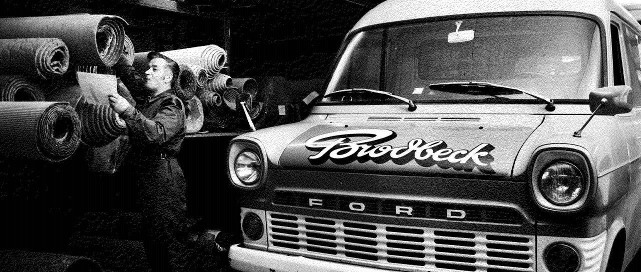 Bild Generation 2 - Ford Ein schwarz weiss Bild eines Ford mit Brodbeck Logo im Lager, ein Mann steht daneben.
